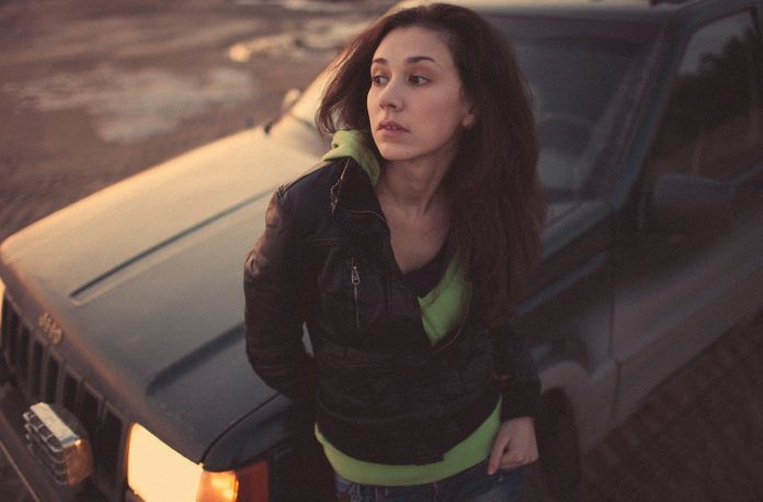 woman-in-black-leather-jacket-standing-beside-black-car-4640808-696x458